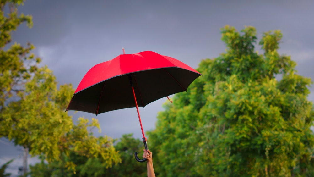 woman holding a big red umbrella On a day when the sky was overcast, and windy it seemed like a storm was about to happen.