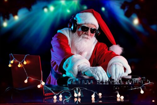 DJ Santa Claus mixing tracks in a nightclub at a Christmas and New Year party or Corporate events. Senior disc jockey as Santa listening music, headphones, laptop, mixer controller player, turntable.