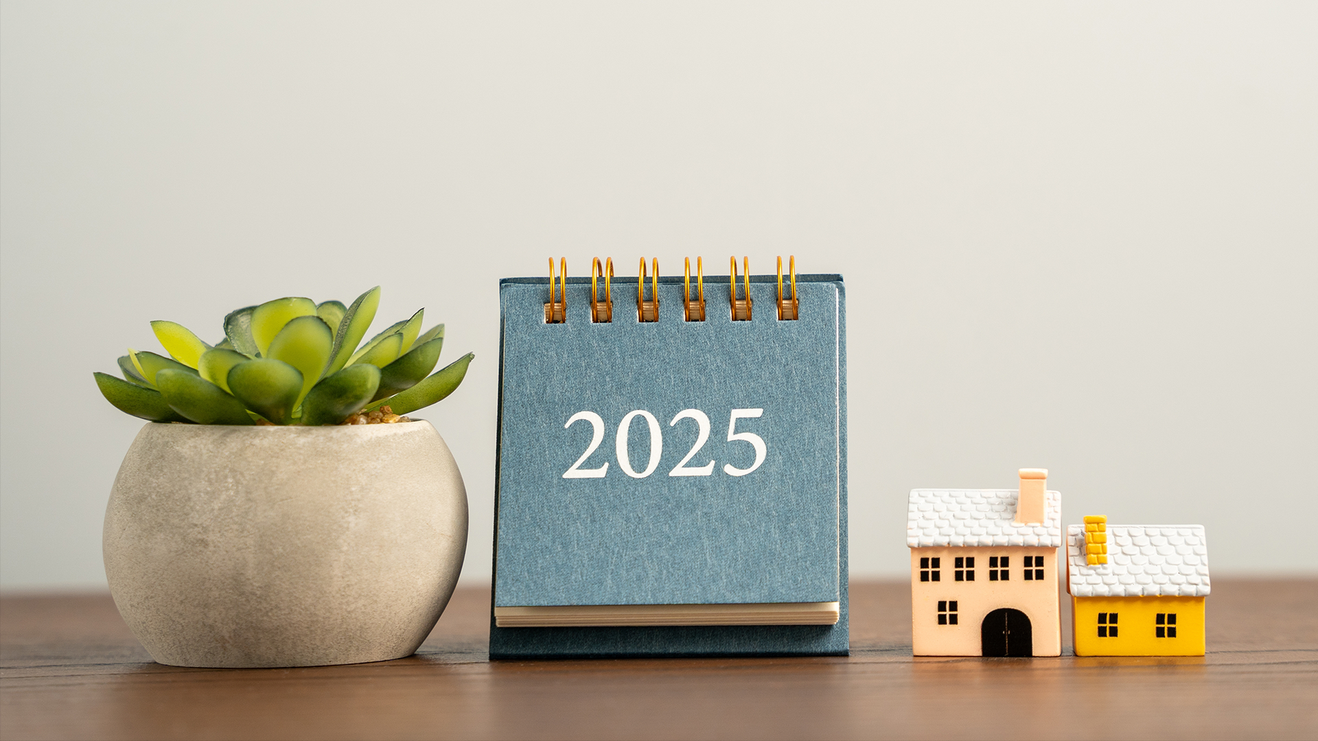 Calendar 2025, houses and succulent on a table. Beginning of a new year. Plan, planning and achieving goals. Real estate market.