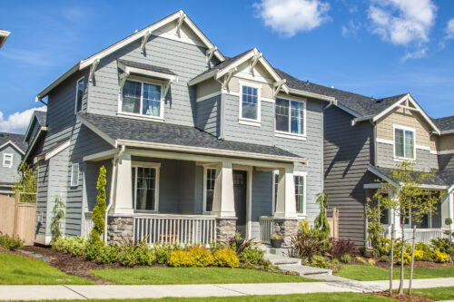 new luxury family house with landscaping on the front and blue sky on background and green grass on front