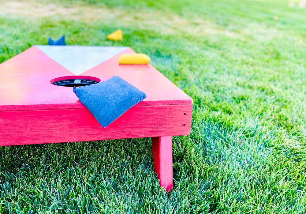 Cornhole board party game on grass in summer