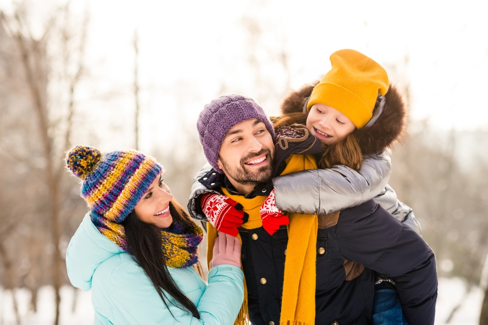 Photo of cheerful family mommy daddy daughter piggyback happy positive smile look each other winter trip outdoors