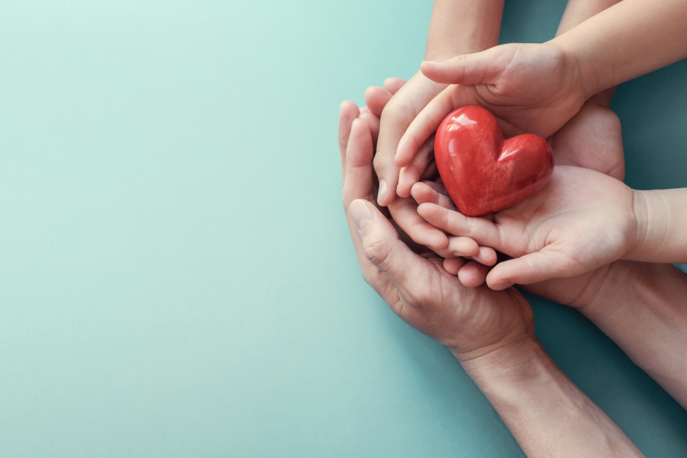 Family hands holding red heart