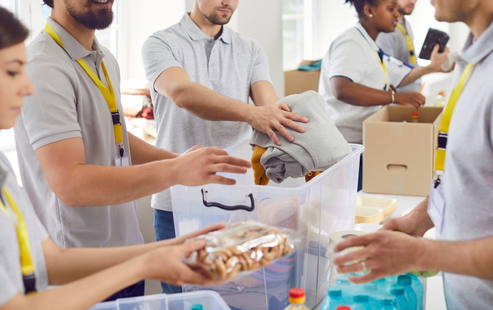 Volunteers working at humanitarian aid center. Diverse Caucasian and African American men and women collect food and clothes to take them to people in refugee shelters. 