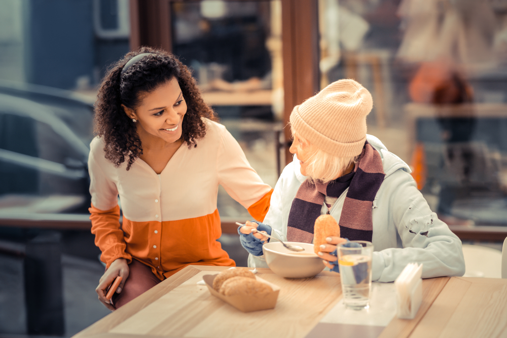 woman buying soup for homeless woman, random act of kindness